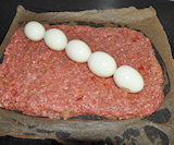 de eieren op het gehakt  leggen